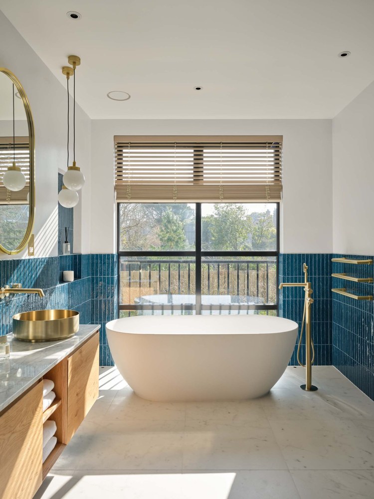 Completed private residential bathroom with blue tile and freestanding bath